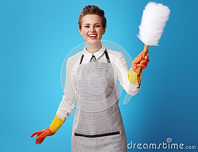 Happy young housemaid using dust cleaning brush on blue Stock Photo