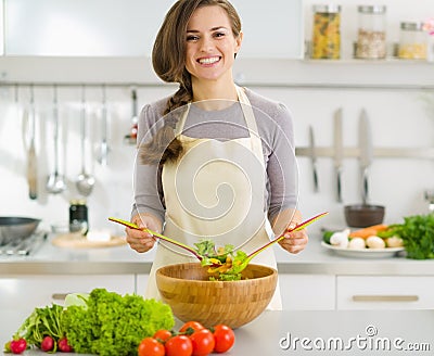 Happy young housewife mixing vegetable salad Stock Photo