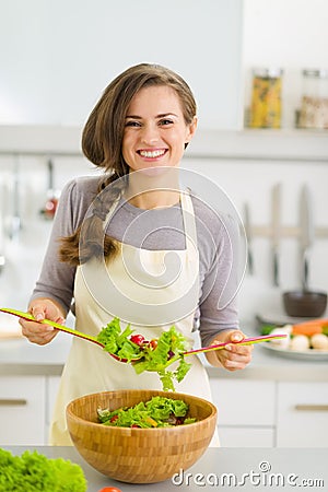 Happy young housewife mixing vegetable salad Stock Photo