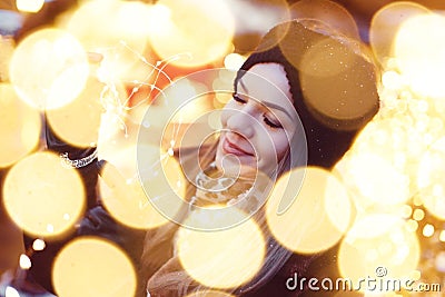 Young imaginative woman holding fairy lights in bokeh at Christmas market Stock Photo