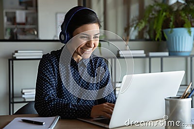 Happy young indian ethnicity female manager in headphones working remotely. Stock Photo