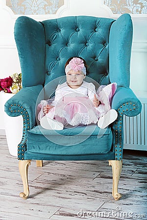 Happy young infant girl sitting in big chair Stock Photo