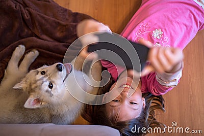 Happy young kid taking a selfie with her husky dog puppy Stock Photo