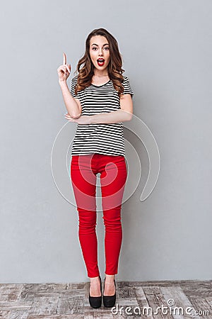 HAppy young lady standing over grey wall have an idea Stock Photo