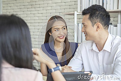 Happy young loving couple talking to their real estate agent with smile looking at house , Planning for the future of the family Stock Photo