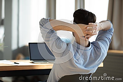 Happy young male worker employee resting on chair during workday. Stock Photo
