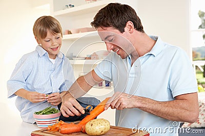Happy young man with boy peeling vegetables Stock Photo