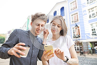 Happy young man with a cup of coffee and a girl with a smartphone listen to music in the headphone Stock Photo