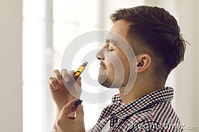 Happy young man enjoying aromatherapy and smelling essential oil from roller bottle Stock Photo