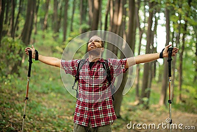 Happy young man enjoying a perfect peaceful moment during hike through forest. Arms outstretched Stock Photo