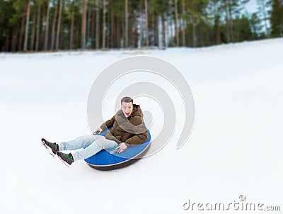 Happy young man sliding down on snow tube Stock Photo