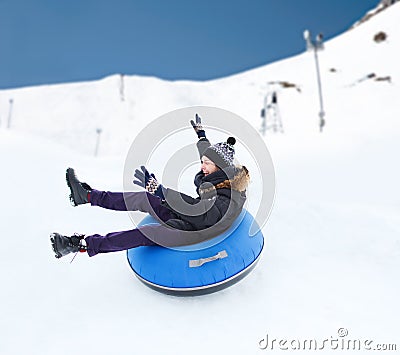 Happy young man sliding down on snow tube Stock Photo