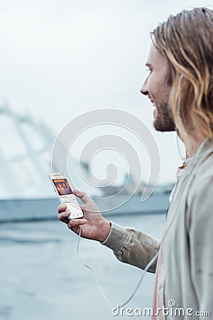 happy young man using smartphone with soundcloud app on screen Editorial Stock Photo