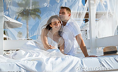 Happy young man and woman sitting under a beautiful white baldachin Stock Photo