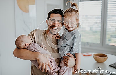 Happy young man taking care of his newborn baby and little daughter indoors at home, paternity leave Stock Photo