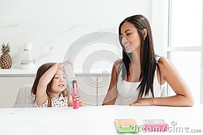 Happy young mom with little daughter drawing with pencils. Stock Photo