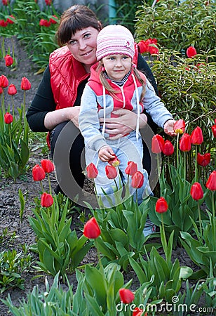 Happy young Mother with baby playing in a field of tulips Stock Photo