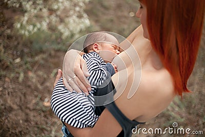 Happy young mother breastfeed newborn baby on walk. Stock Photo