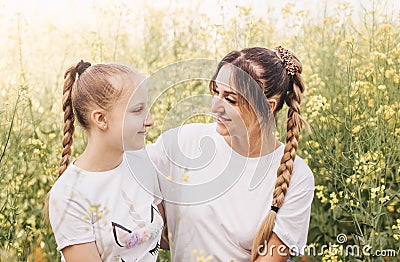 Happy young mother cuddles with her daughter in the summer on the field of rape. Happiness with family Stock Photo