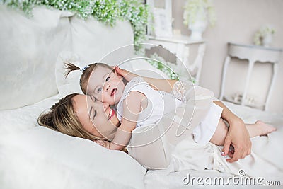 Happy young mother hugs her little baby on a bed Stock Photo
