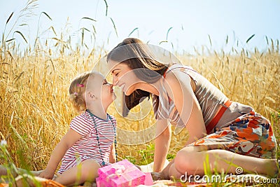 Happy young mother with little daughter on field in summer day Stock Photo