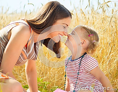 Happy young mother with little daughter on field in summer day Stock Photo