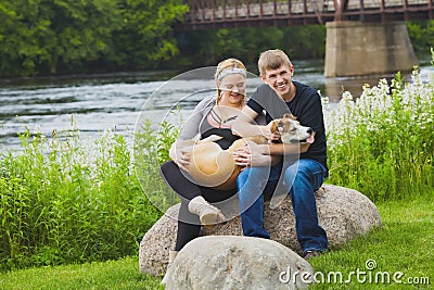 Happy young owners holding dog and stroking it Stock Photo