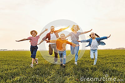 Happy family running in field in summer evening Stock Photo