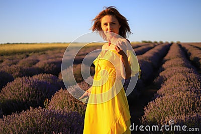 Happy young pretty woman walks at sunset in a lavender field with a bouquet in her hands and enjoys solitude with nature Stock Photo