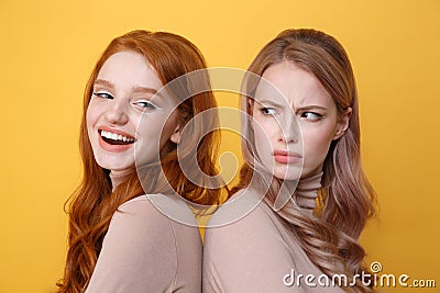 Happy young redhead lady near angry blonde woman. Stock Photo