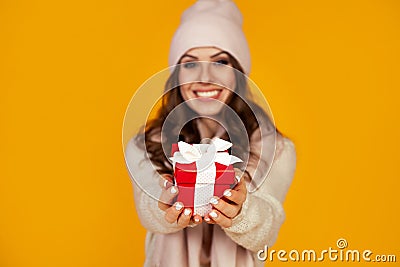 Happy young smiling woman holding and holding red gift box in front, offering and giving Christmas gifts. A girl in a sweater Stock Photo