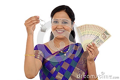 Happy young traditional woman holding Indian currency and house Stock Photo