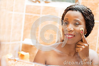Happy young woman applies cream on her face Stock Photo