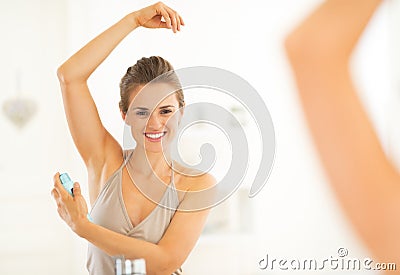 Happy young woman applying deodorant on underarm Stock Photo
