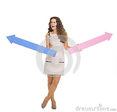 Happy young woman with arrows pointing in opposite ways Stock Photo