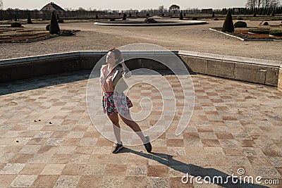 Happy young woman dancing in an empty fountain wearing a colorful skirt Stock Photo