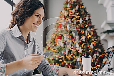 Happy young woman doing online shopping on laptop computer at home during Winter holidays sales Stock Photo