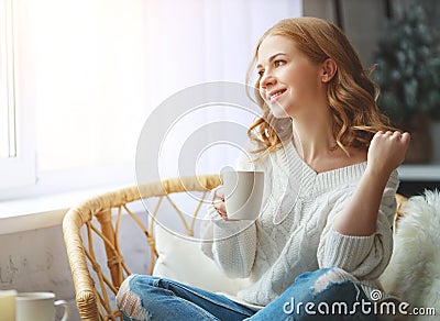 Happy young woman drinking morning coffee by window in winter Stock Photo