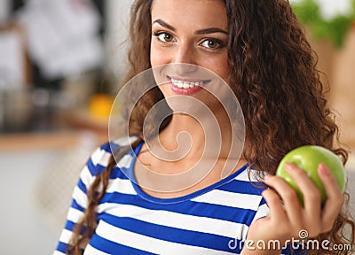 Happy young woman eating apples on kitchen Stock Photo