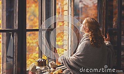 Happy young woman enjoying fresh autumn air at open window Stock Photo