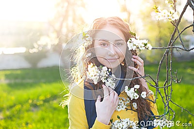 Happy young woman enjoying smell flowers over spring garden background Stock Photo