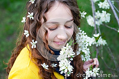 Happy young woman enjoying smell flowers over spring garden background Stock Photo