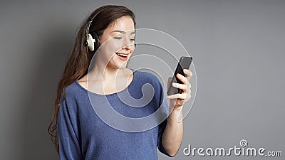 Happy young woman with headphones streaming music on her smartphone Stock Photo