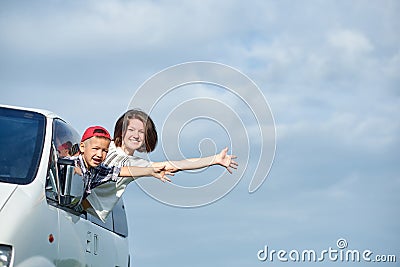 Happy young woman and her child looking out from windows. Family travelling by car Stock Photo