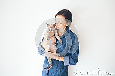 Happy young woman with her Devon Rex cat. Young woman is holding and hugging her cute curious Devon Rex cat. Cat is feeling Stock Photo