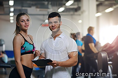 Happy young woman and her personal trainer in gym Stock Photo