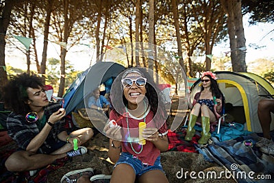 Happy young woman holding bubble wand at campsite Stock Photo