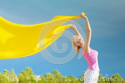 Happy young woman holding yellow scarf in the wind Stock Photo