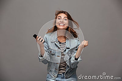 Happy young woman in jeans jacket clenching her fists in winner Stock Photo