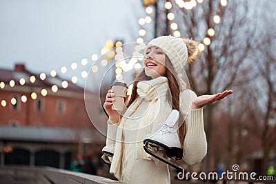 Happy young woman in knitted sweater and hat is going skating and drinks coffee Stock Photo